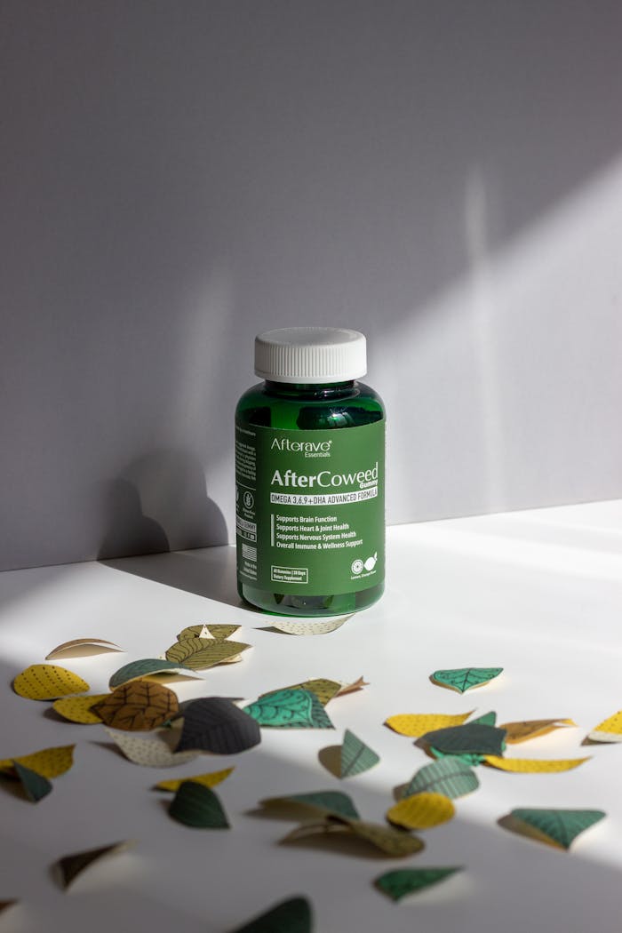 AfterCoweed supplement bottle with decorative leaves in dramatic lighting.